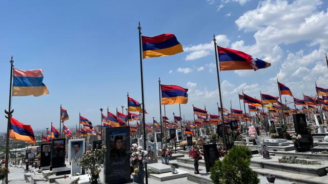 A cemetery with waving Armenian flags and photos.
