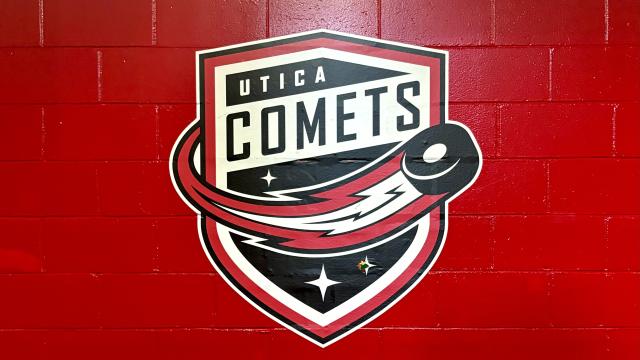 Utica Comets Shield Logo on a Red wall