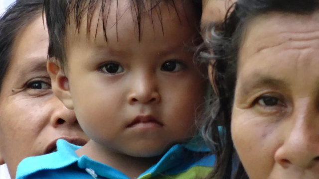 Mother In the background being partially blocked off halfway by her child and a grandma in the front of the image to the right 