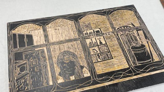 woodblock with image carved and covered in black in on a glass table