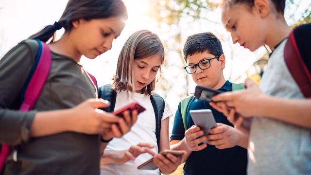 Four teenagers using smartphones
