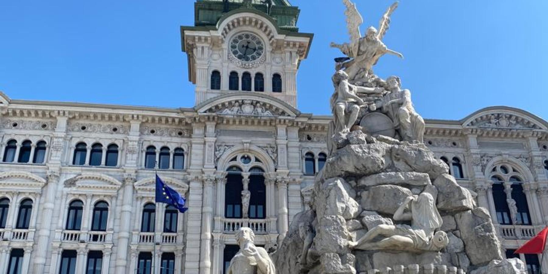 Photo of an ornate statue and decorated white stone building.