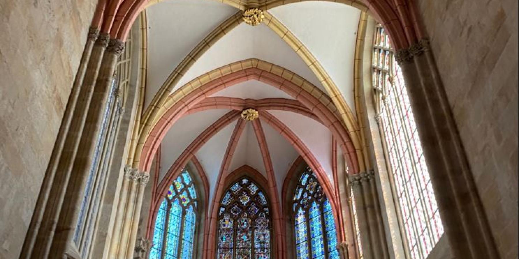 Photo of stained glass windows and vaulted ceilings in a cathedral.