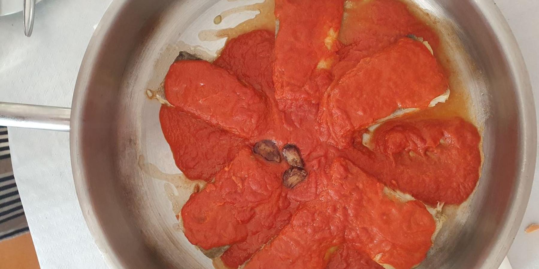 A silver metal pan with red sauce in it.