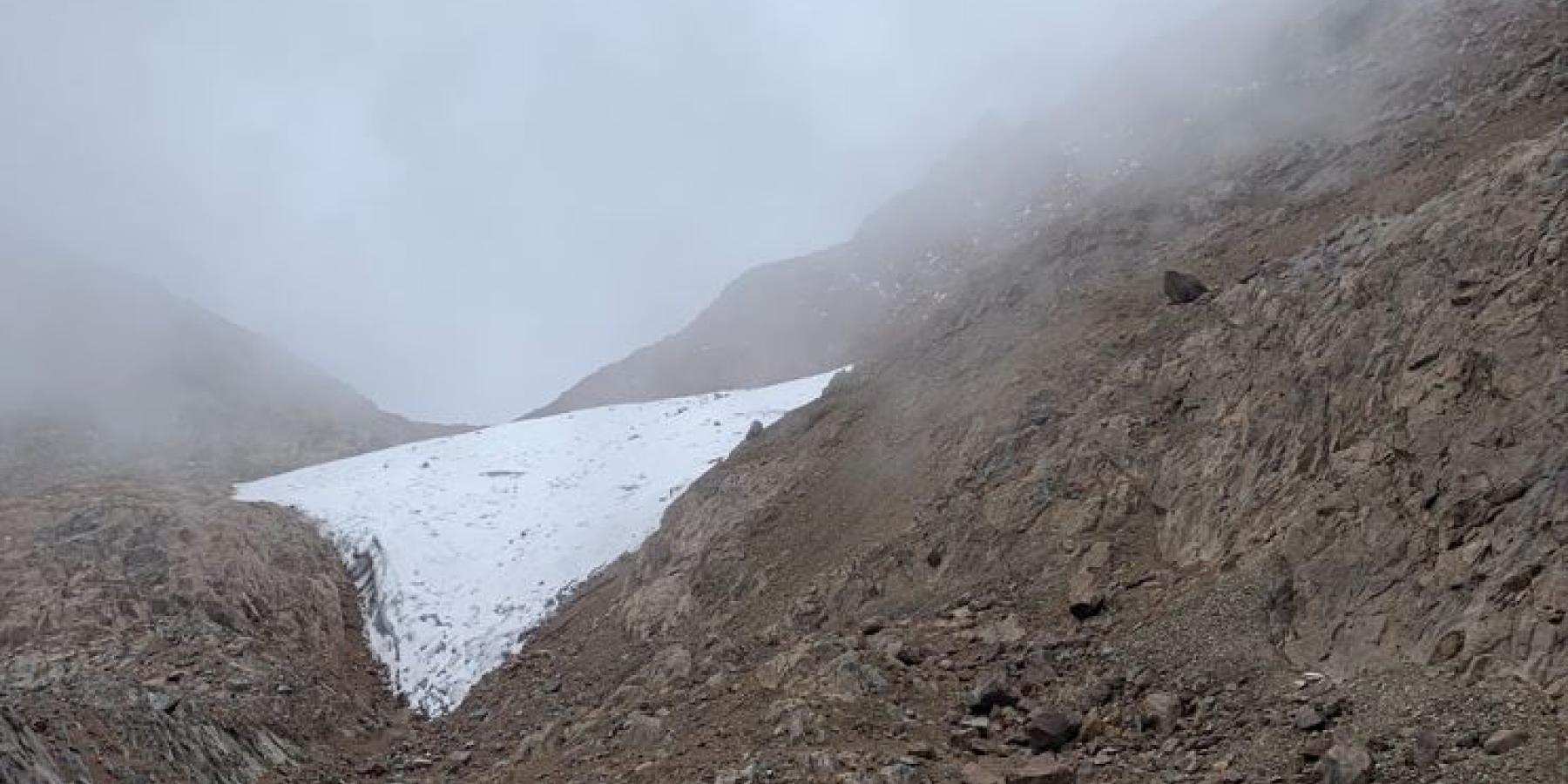 Rocks, mist, and snow on the side of a mountain.