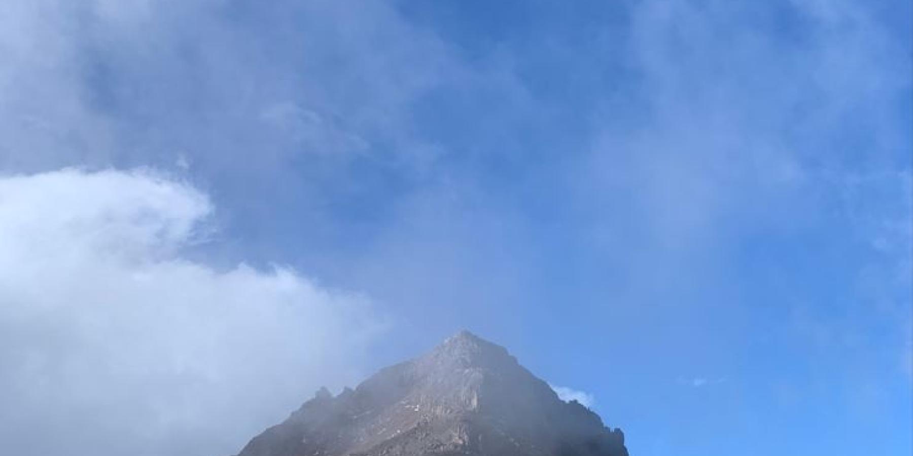 Clouds roll over a mountain peak.