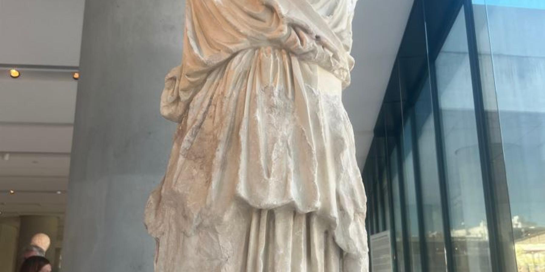 A white marble statue of a woman&#039;s body.