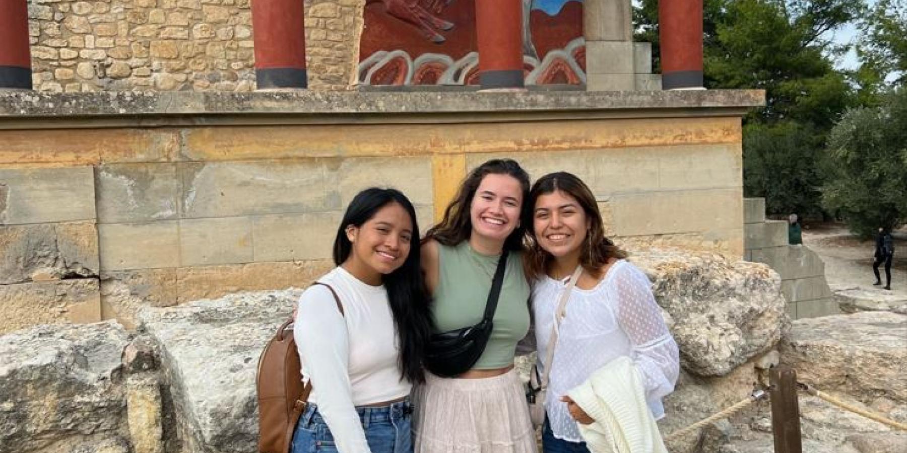 Courtney and two friends stand by Greek ruins of a building.
