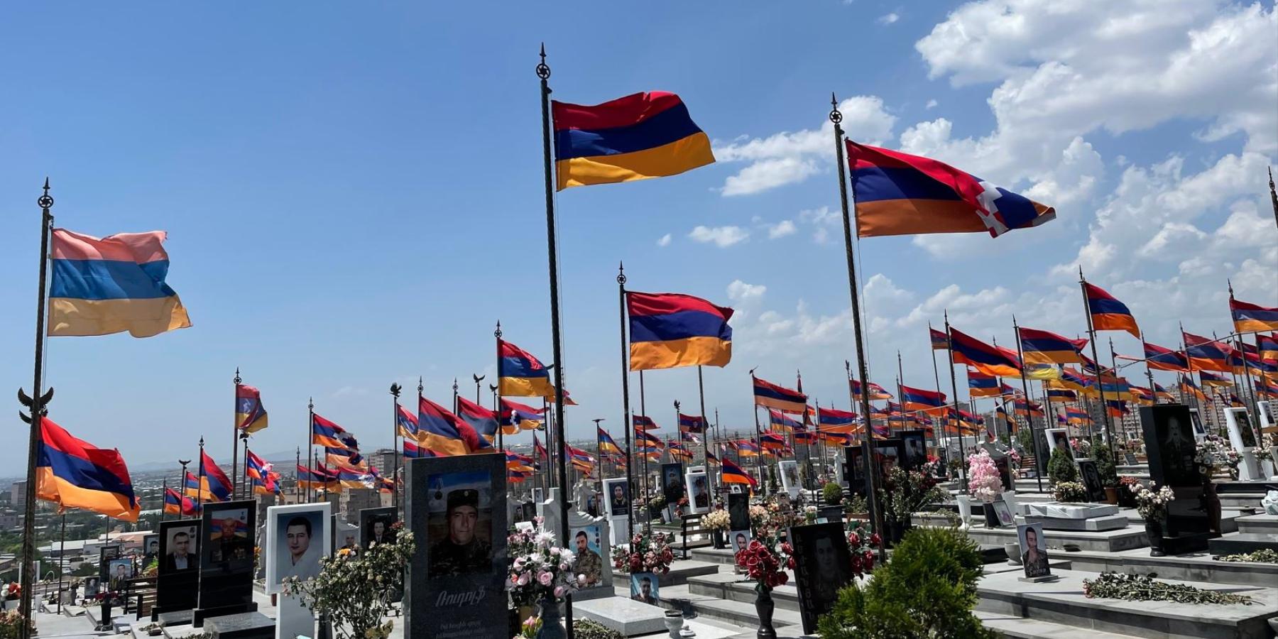 A cemetery with waving Armenian flags and photos.