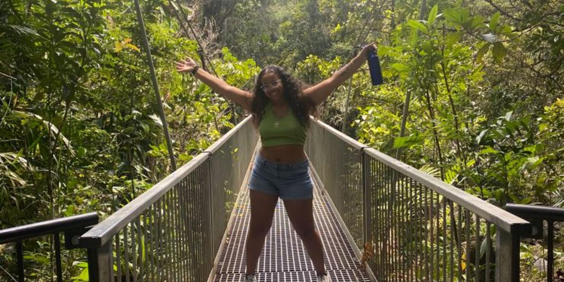 Luisa poses on a bridge surrounded by leafy trees.