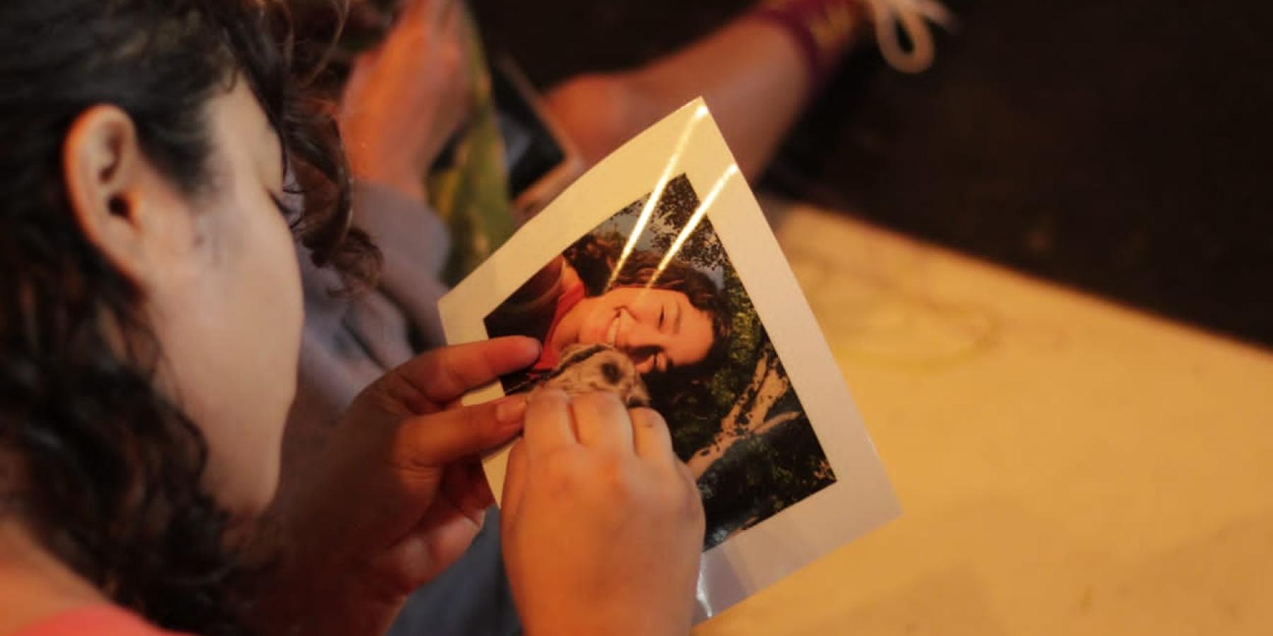 Fernanda embroidening a photograph of her service dog Mika and her as part of a workshop.