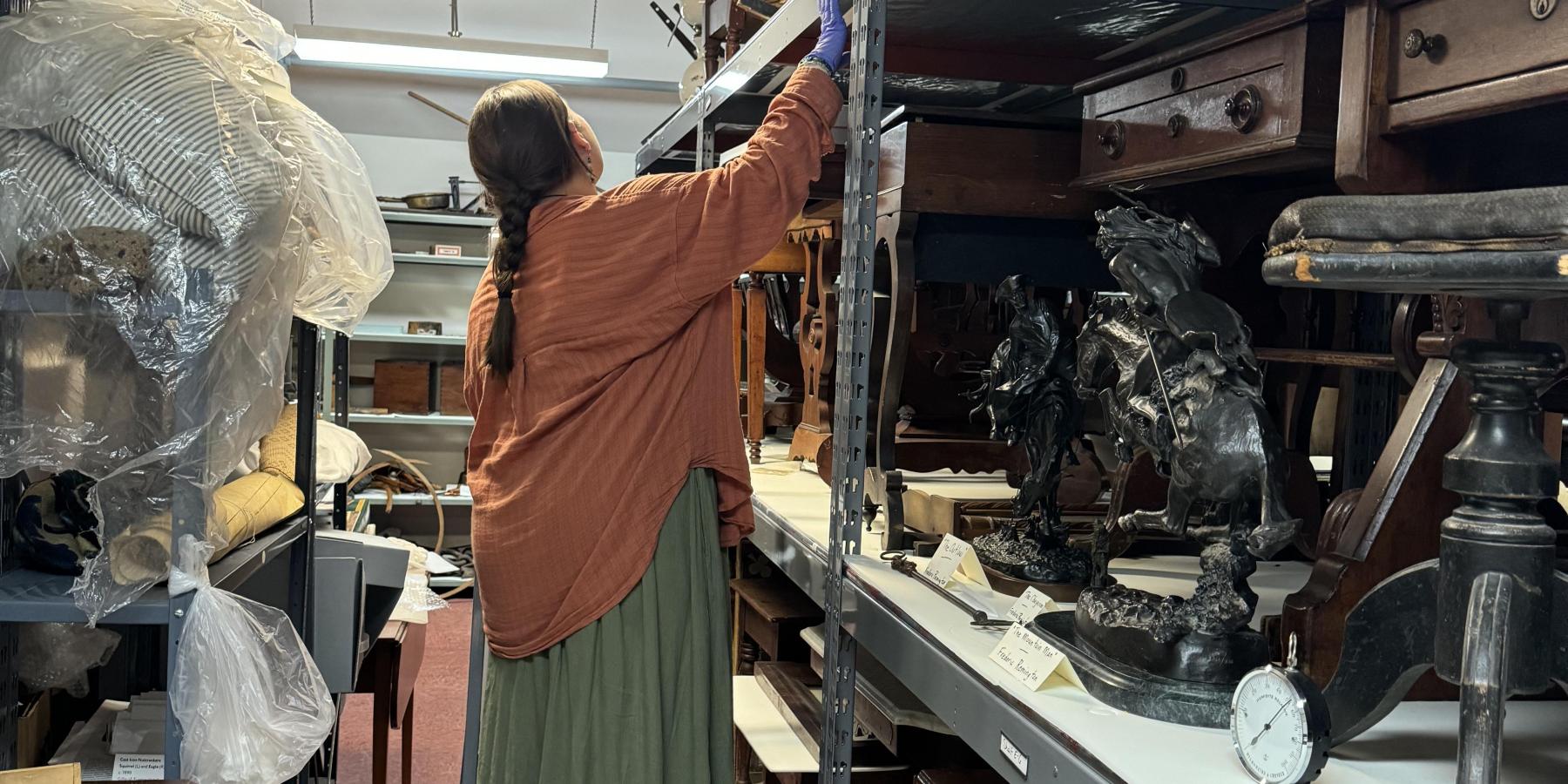 A woman in orange standing on a ladder.
