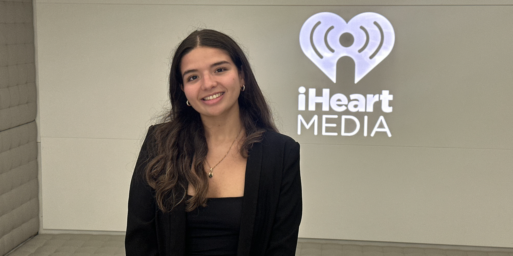 iHeartMedia headquarters, standing in front of the illuminated company logo after completing my summer internship with the Product Data Analytics team.