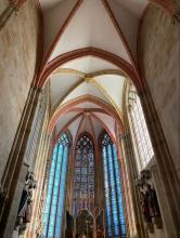 Photo of stained glass windows and vaulted ceilings in a cathedral.