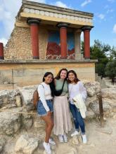 Courtney and two friends stand by Greek ruins of a building.