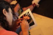 Fernanda embroidening a photograph of her service dog Mika and her as part of a workshop. 