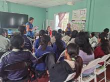 A group of school-aged girls from the Little Sisters fund program standing up one by one giving self- introductions. The program manager, co-founder, and I are in the background. 