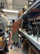 A woman in orange standing on a ladder.