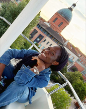 A smiling person poses on a ferris wheel with the Chapelle de La Grave in the background
