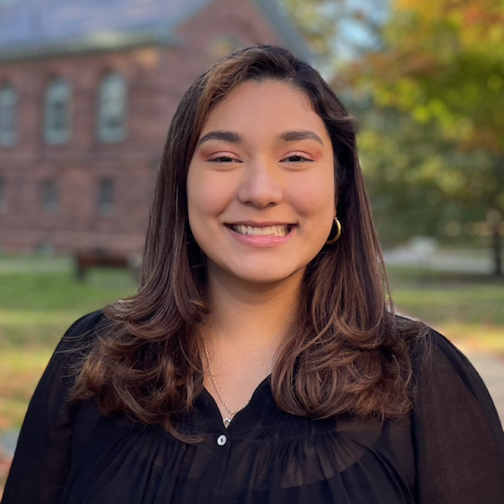 Fernanda appears smiling in the center of the photo, she is wearing a black long sleeve shirt.