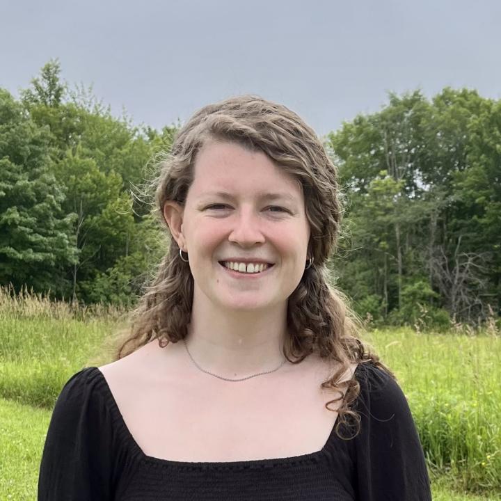 Evelyn can be seen standing in front of a wooded background.