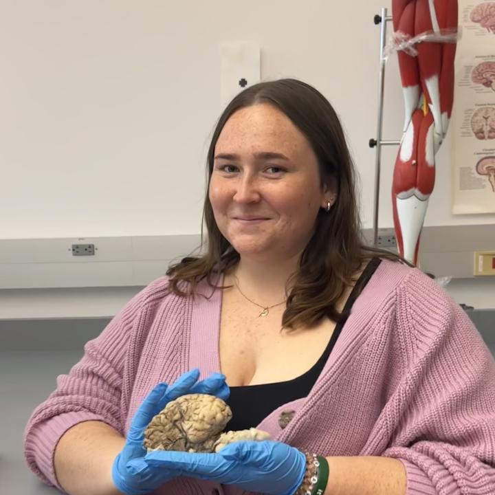 Sara St. Clair holding a preserved brain specimen in a neuroscience lab.
