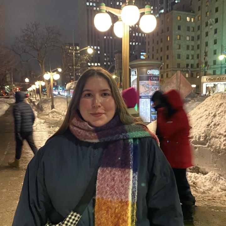 A woman standing in a winter setting with a colorful scarf.