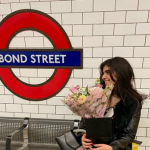 Mariam sits in the London Tube with a bouquet of flowers.