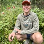 Skylar is crouching in a field of wildflowers in her hometown of Victor, Idaho and smiling.