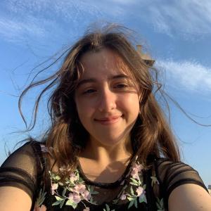 Grace Cicchinelli smiling at the camera in front of a bright blue sky.
