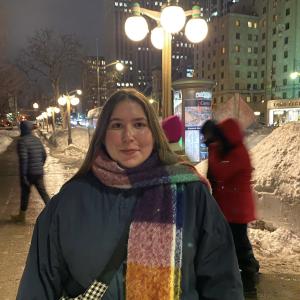 A woman standing in a winter setting with a colorful scarf.