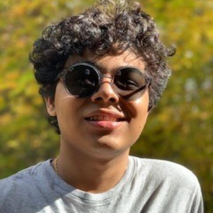 Photo of me with sun glass. I am wearing a light gray T-Shirt and my hair is wavy and my skin tone is tan.