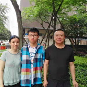 A portrait of Sam Yang and his parents standing together outside.